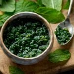 Square image of mint sauce in a small dish on a wooden board