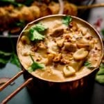 Satay sauce in a small copper pan topped with peanuts and coriander