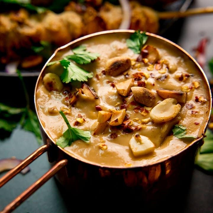 Satay sauce in a small copper pan topped with peanuts and coriander