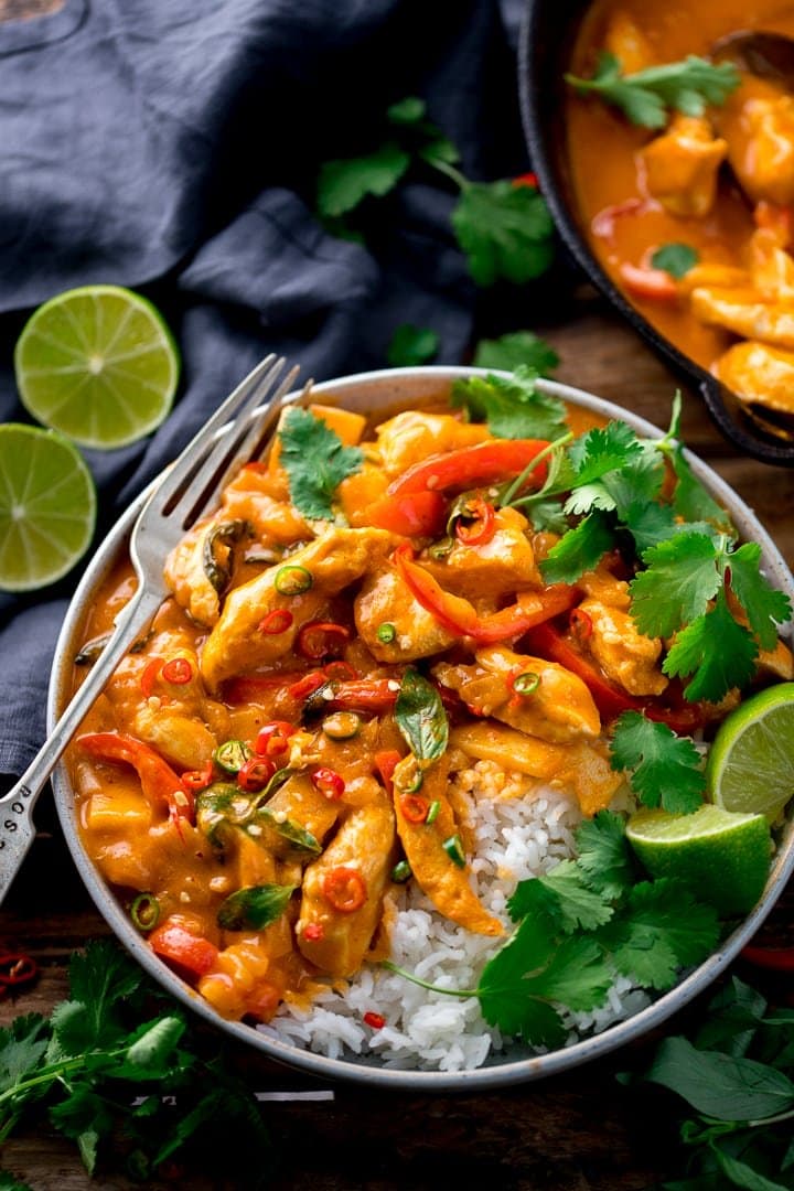 Thai red chicken curry with rice in a bowl with lime and coriander