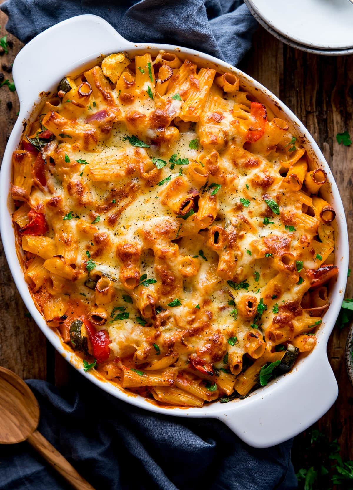 vegetable pasta bake in a white dish next to a blue cloth