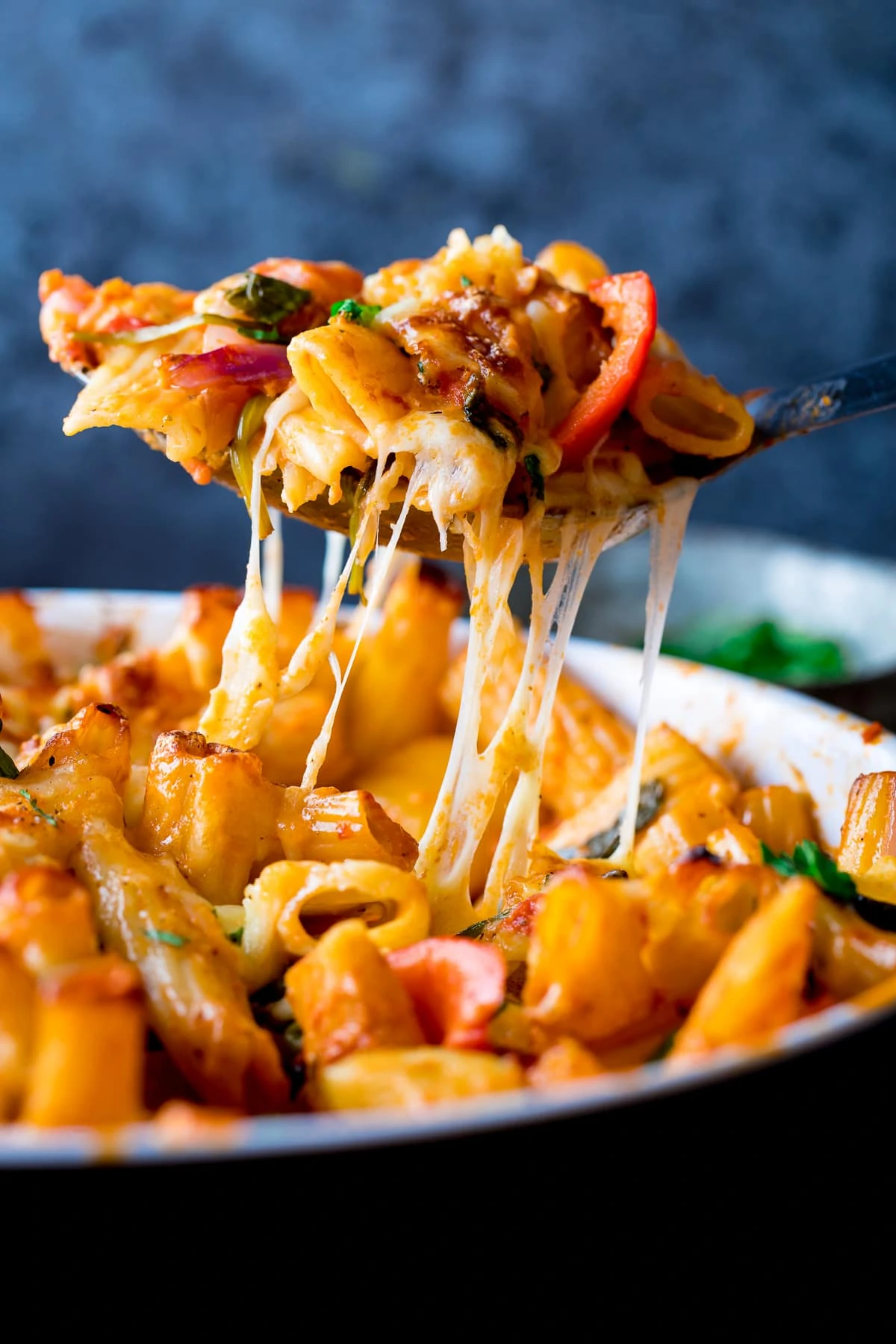 Spoonful of vegetable pasta bake being lifted out of the dish