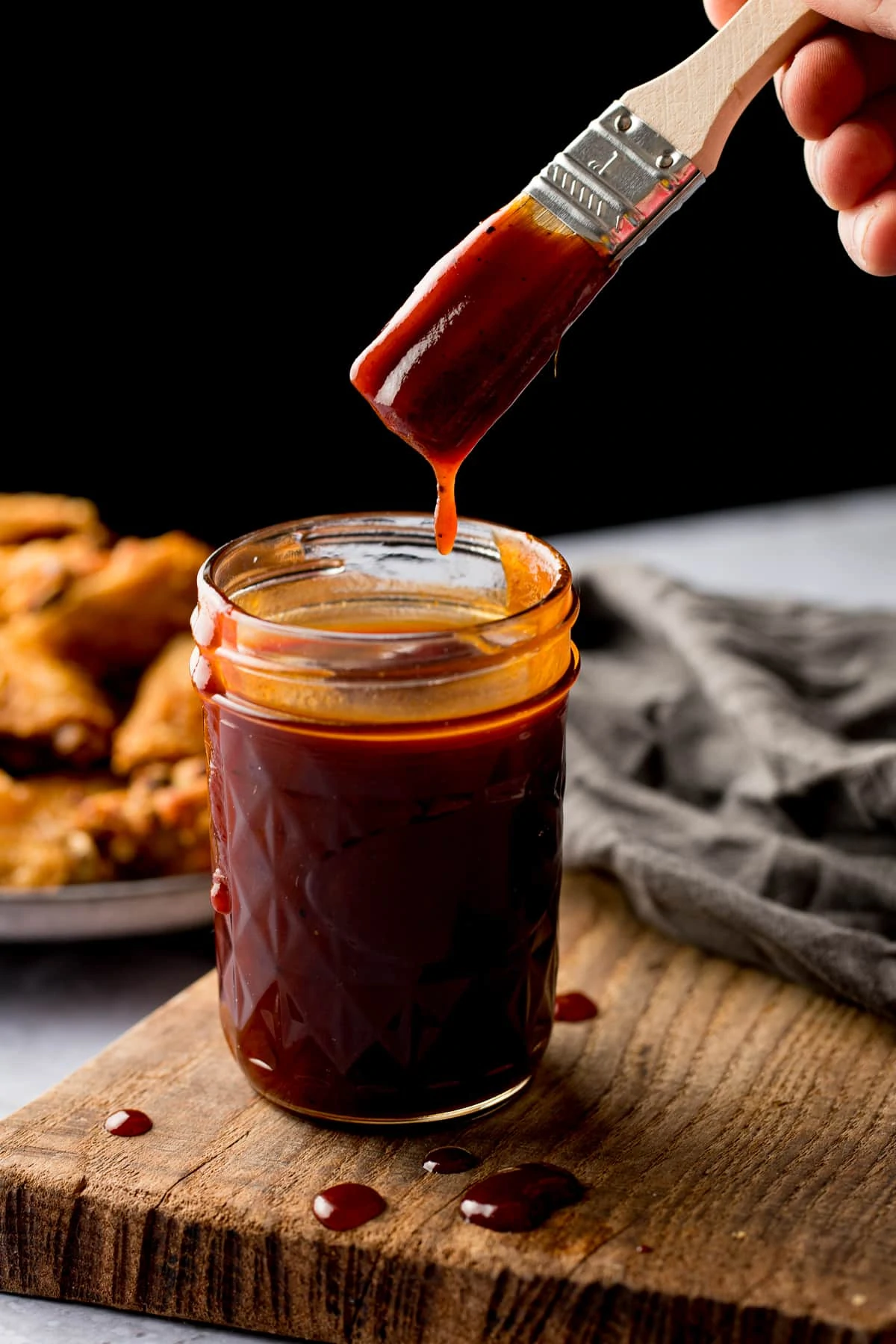 homemade bbq sauce in a jar. A basting brush being dipped in.