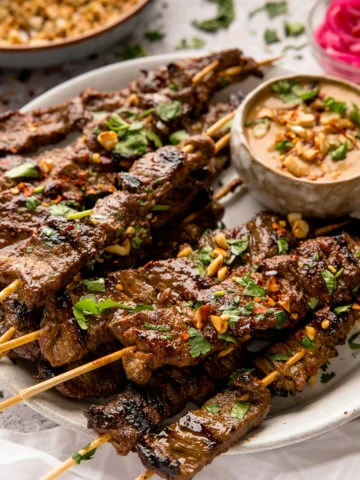 beef satay on wooden skewers on a white plate