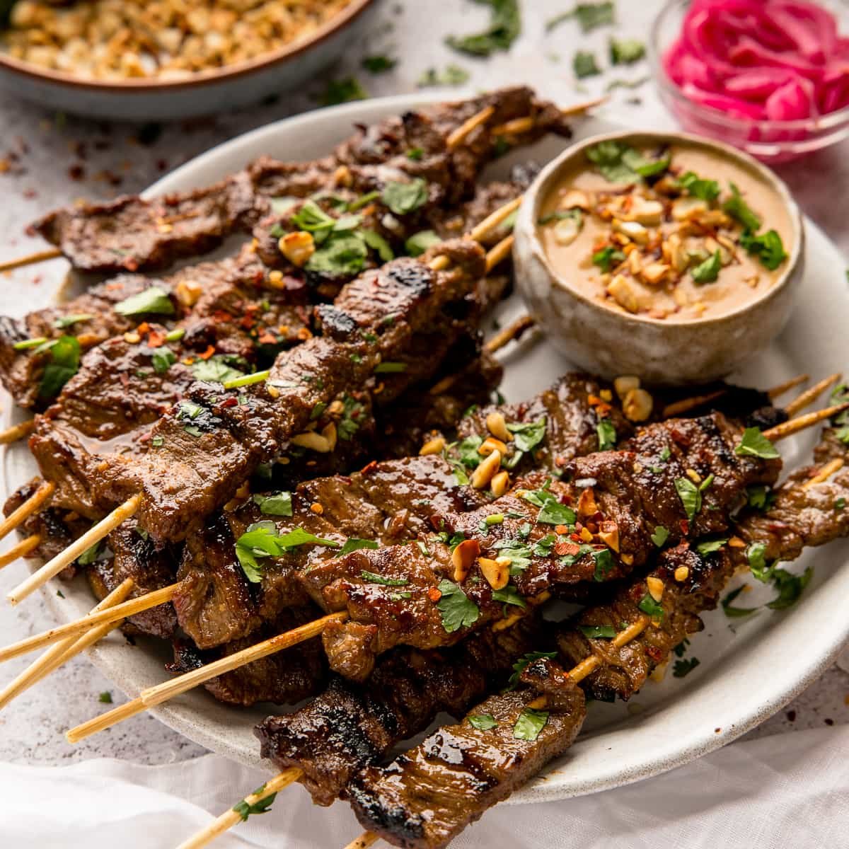 beef satay on wooden skewers on a white plate