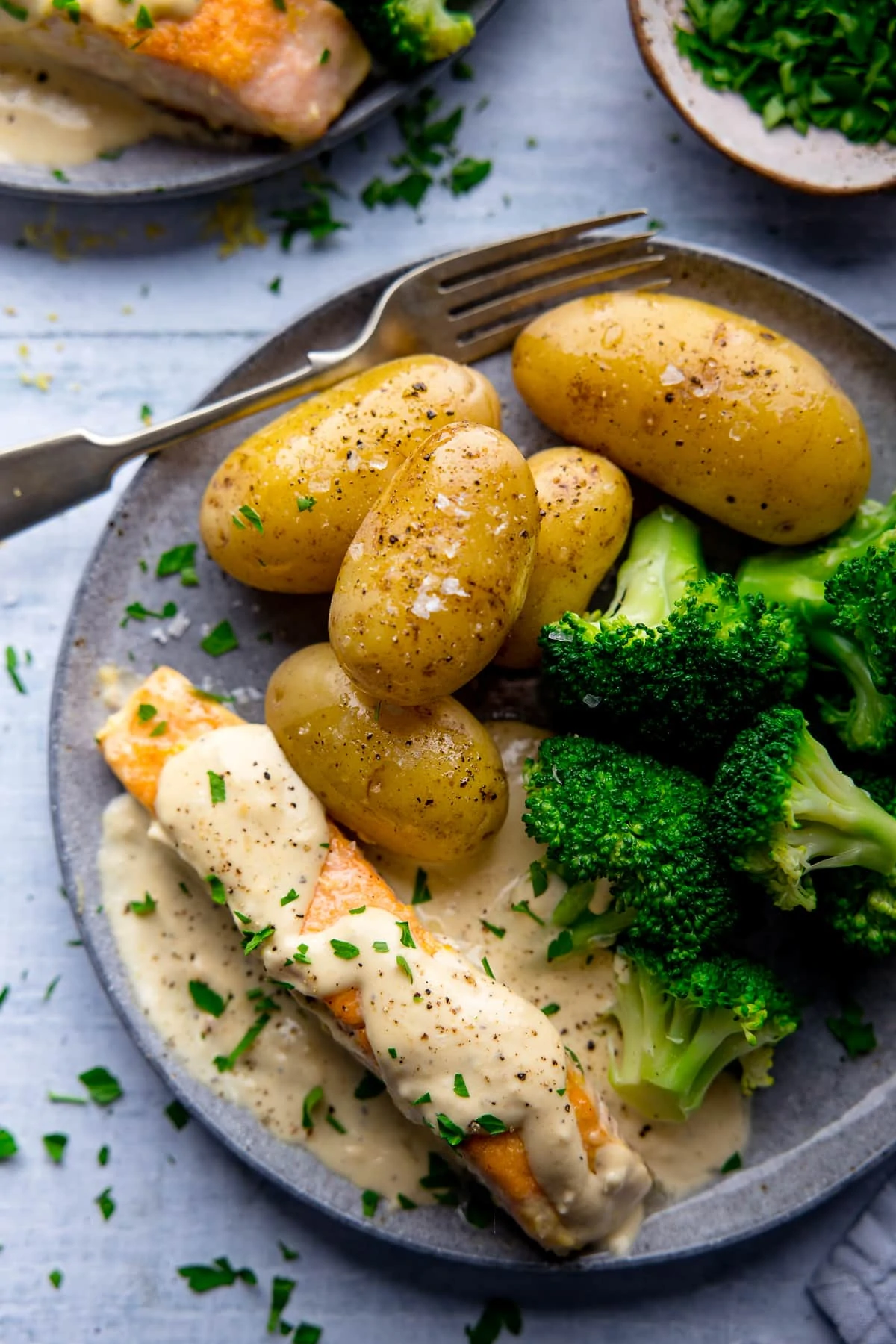 Salmon in cream sauce, broccoli and potatoes on a grey plate