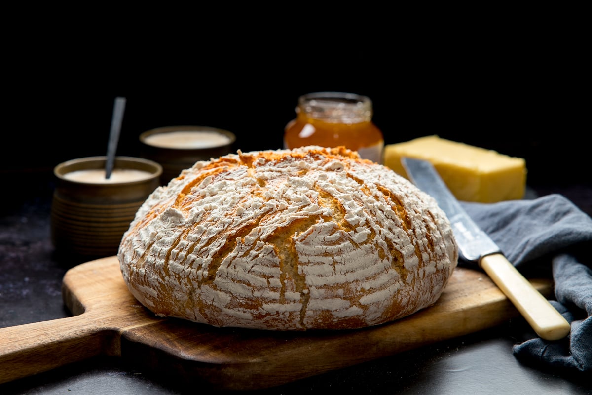 Wide image of a loaf of artisan bread on a wooden chopping board