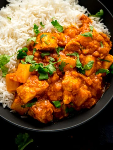 chicken dhansak with rice in a black bowl