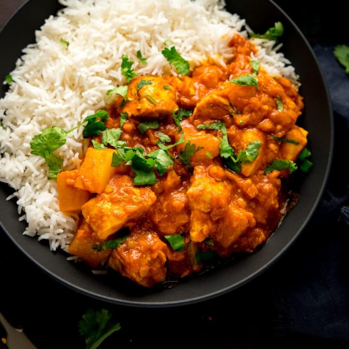 chicken dhansak with rice in a black bowl