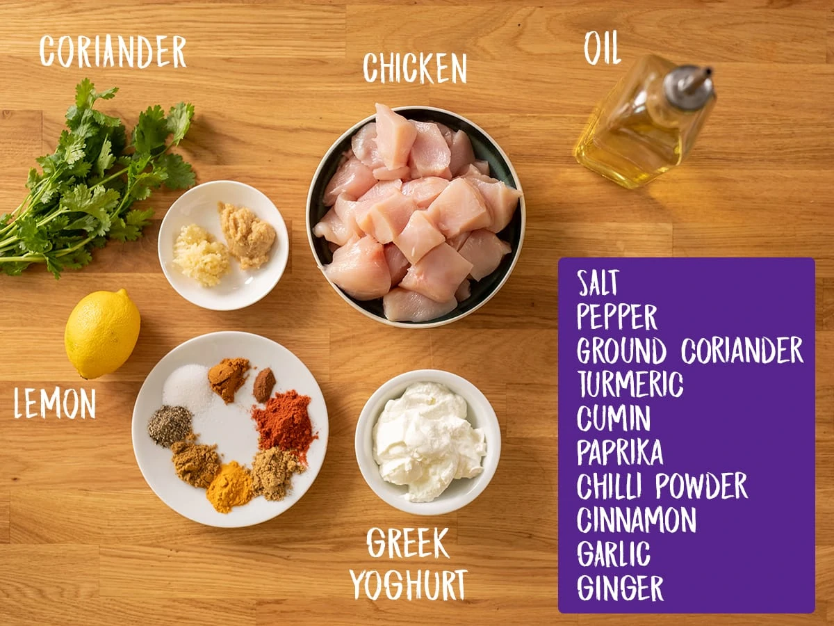 Ingredients for chicken tikka skewers on a wooden board