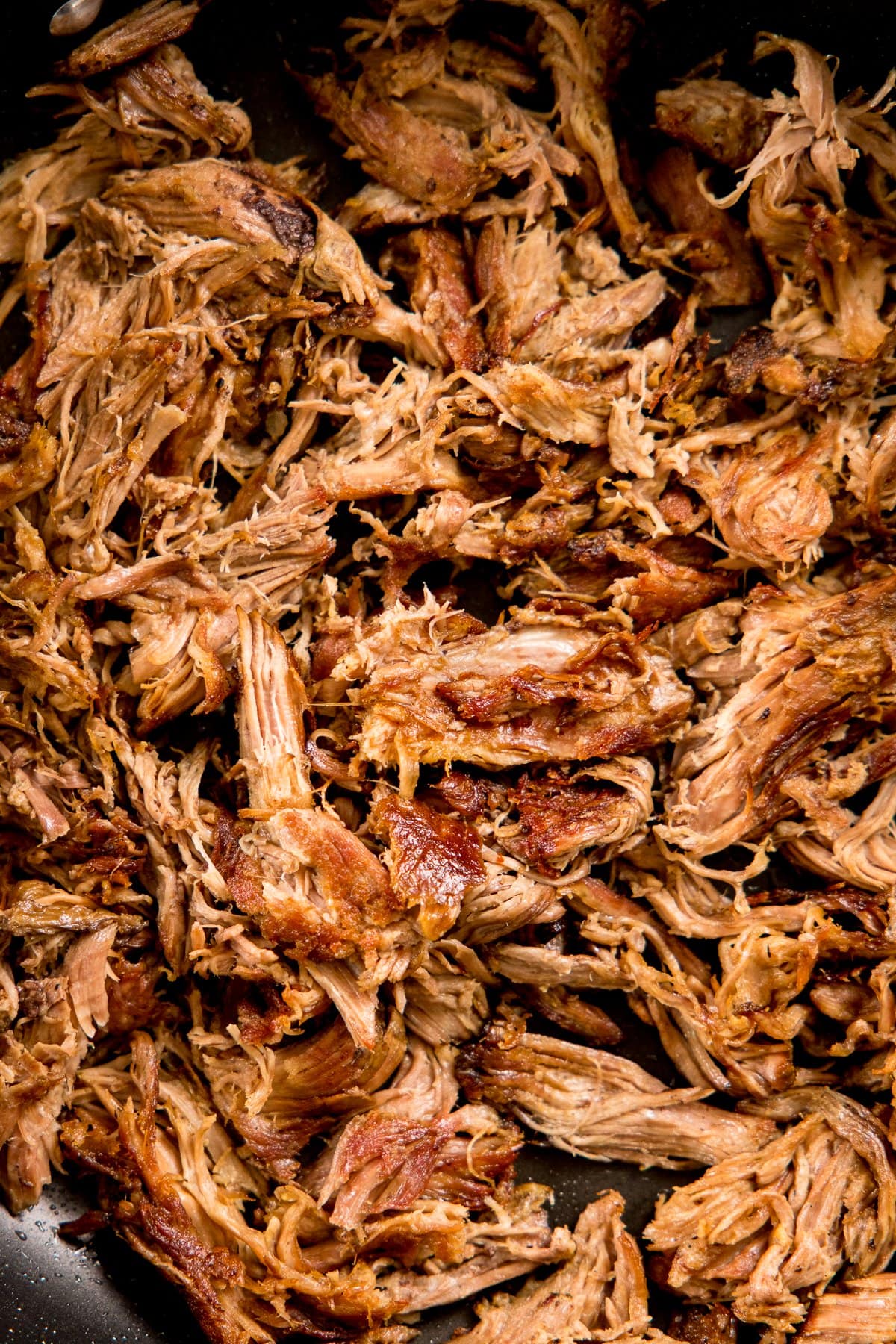 Shredded lamb carnitas in a frying pan