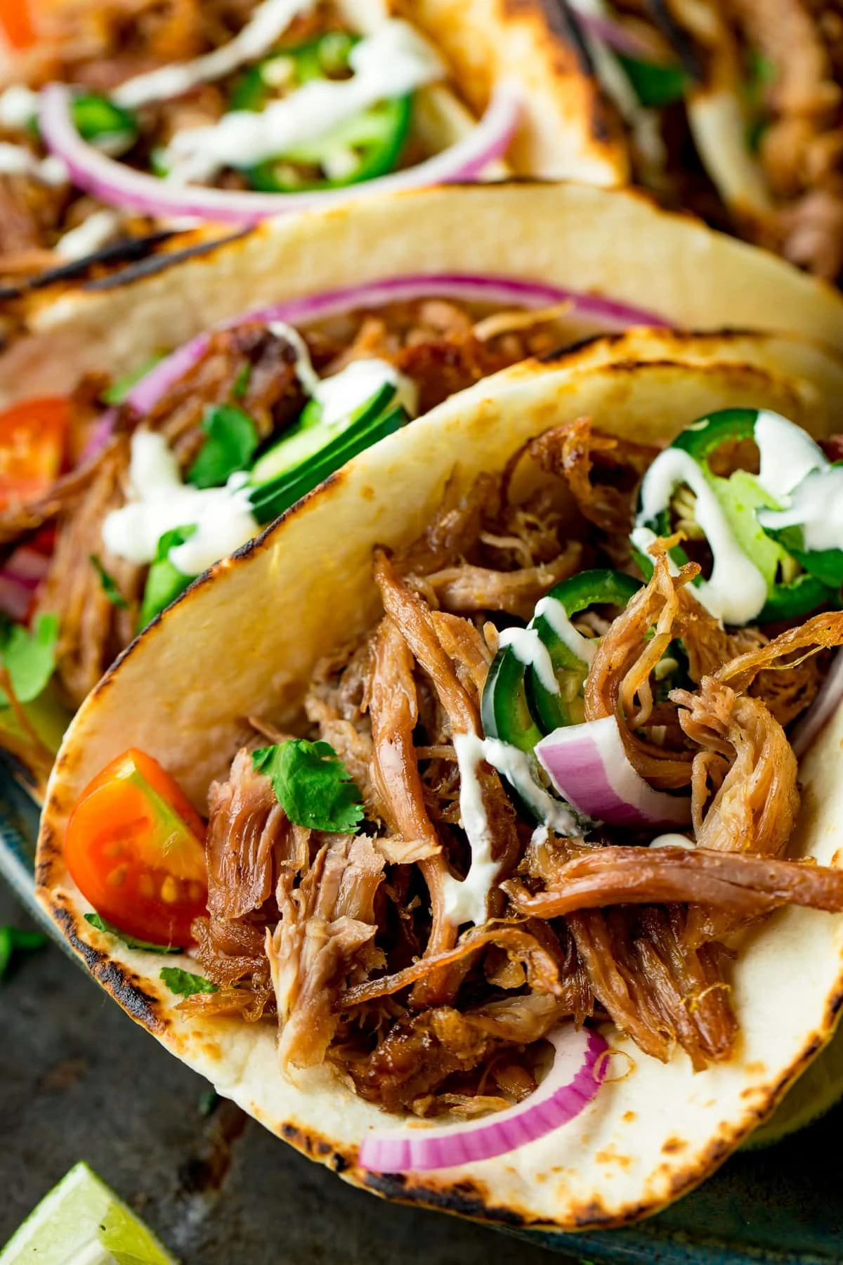 Close up of Lamb Barbacoa Carnitas Tacos with sour cream and red onions