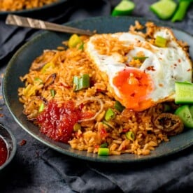 nasi goreng rice on a plate, topped with a fried egg and sweet chilli sauce