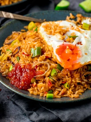 nasi goreng rice on a plate, topped with a fried egg and sweet chilli sauce