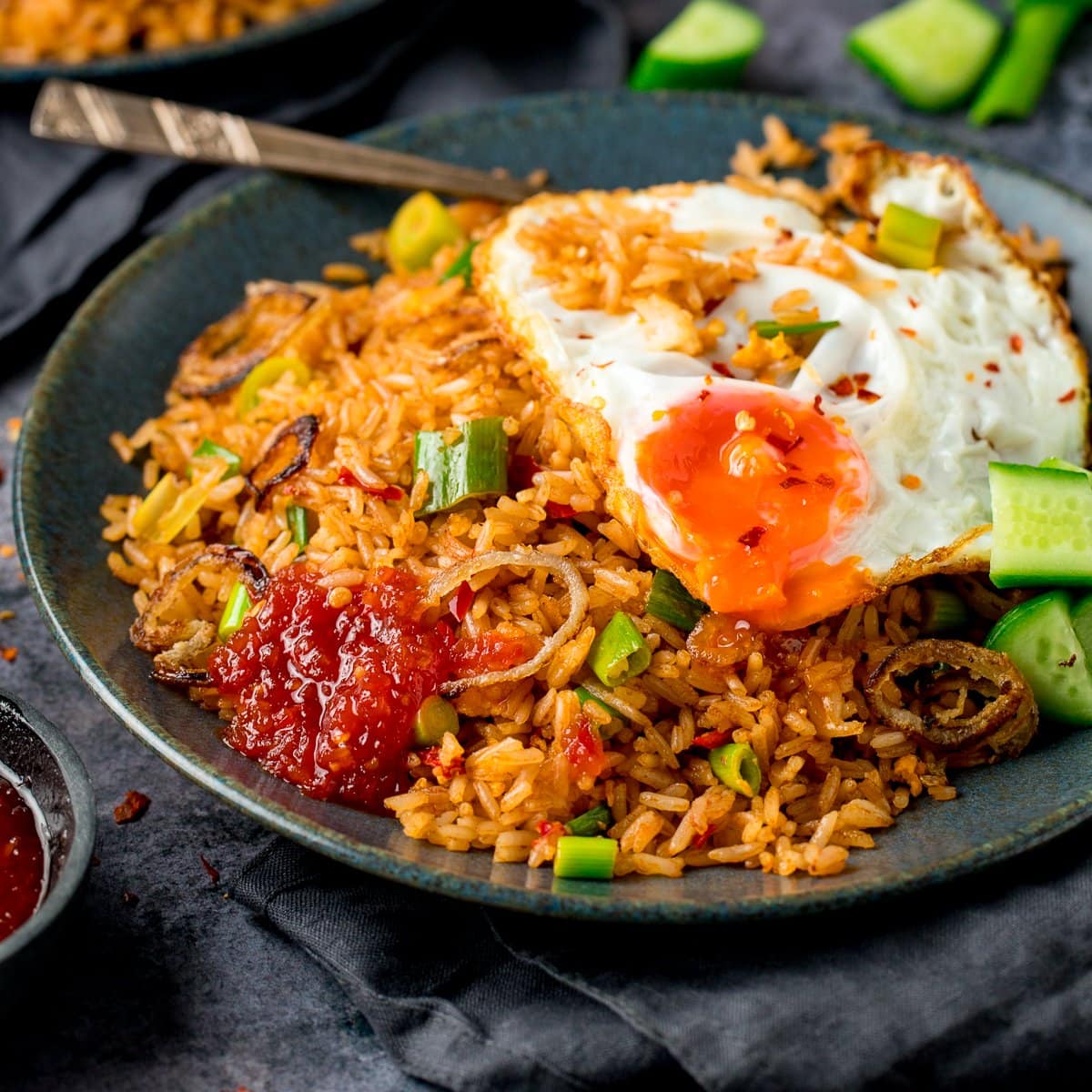 nasi goreng rice on a plate, topped with a fried egg and sweet chilli sauce