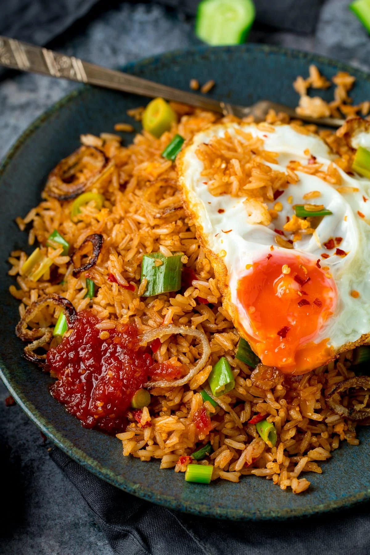 nasi goreng rice on a plate, topped with a fried egg and chilli sauce