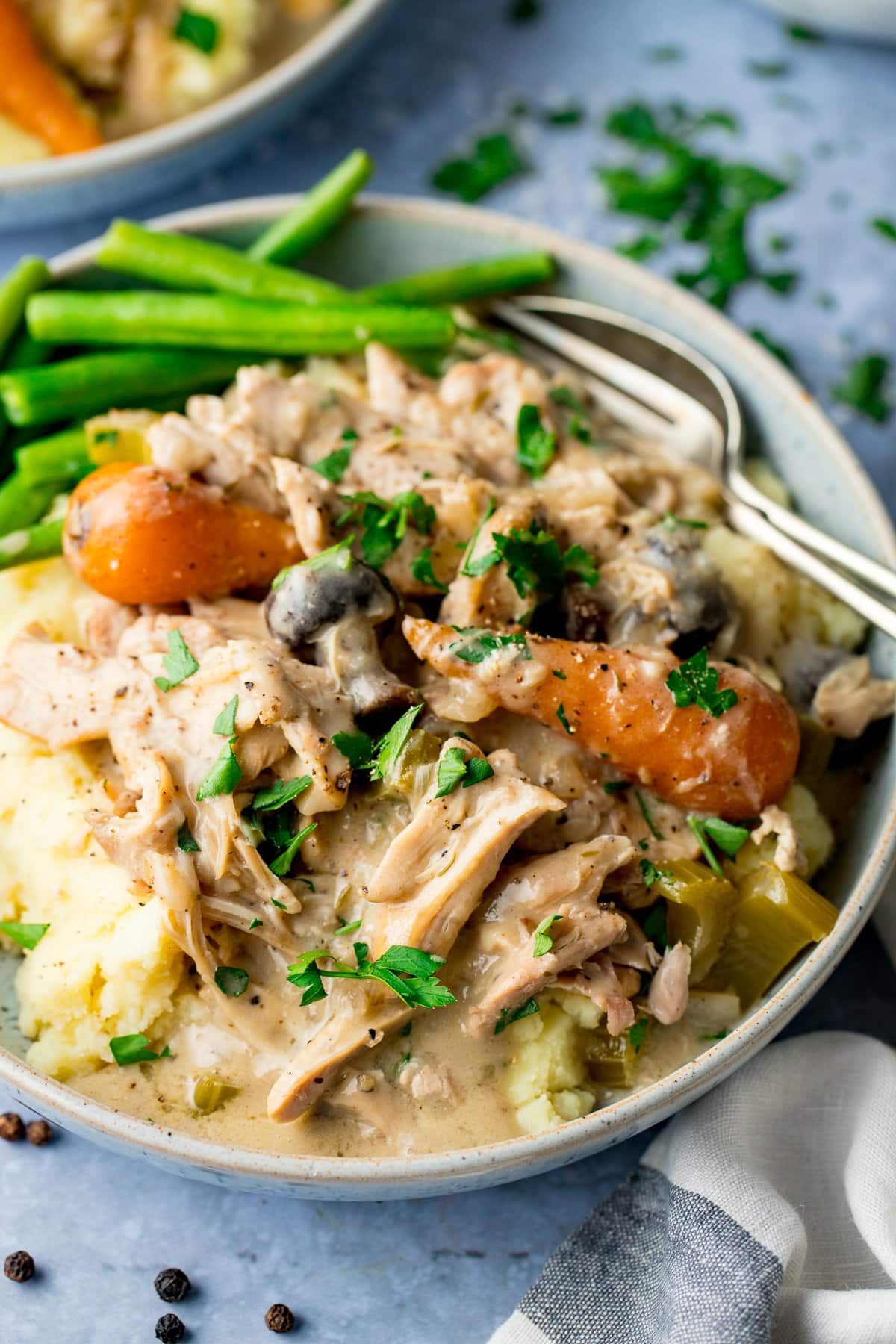 chicken casserole with carrots and mushrooms in a bowl with mashed potatoes and green beans