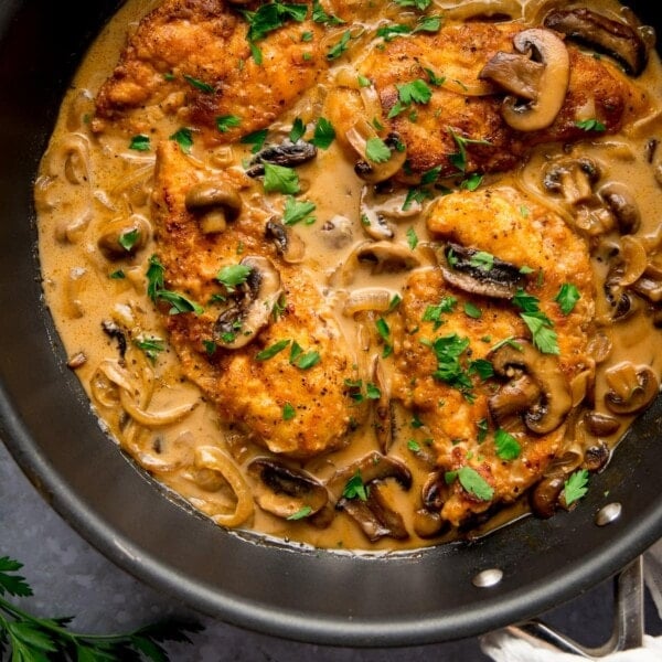 chicken marsala in a pan with mushroom and onions, sprinkled with fresh parsley