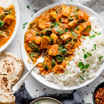 Chicken curry in a white bowl with rice.