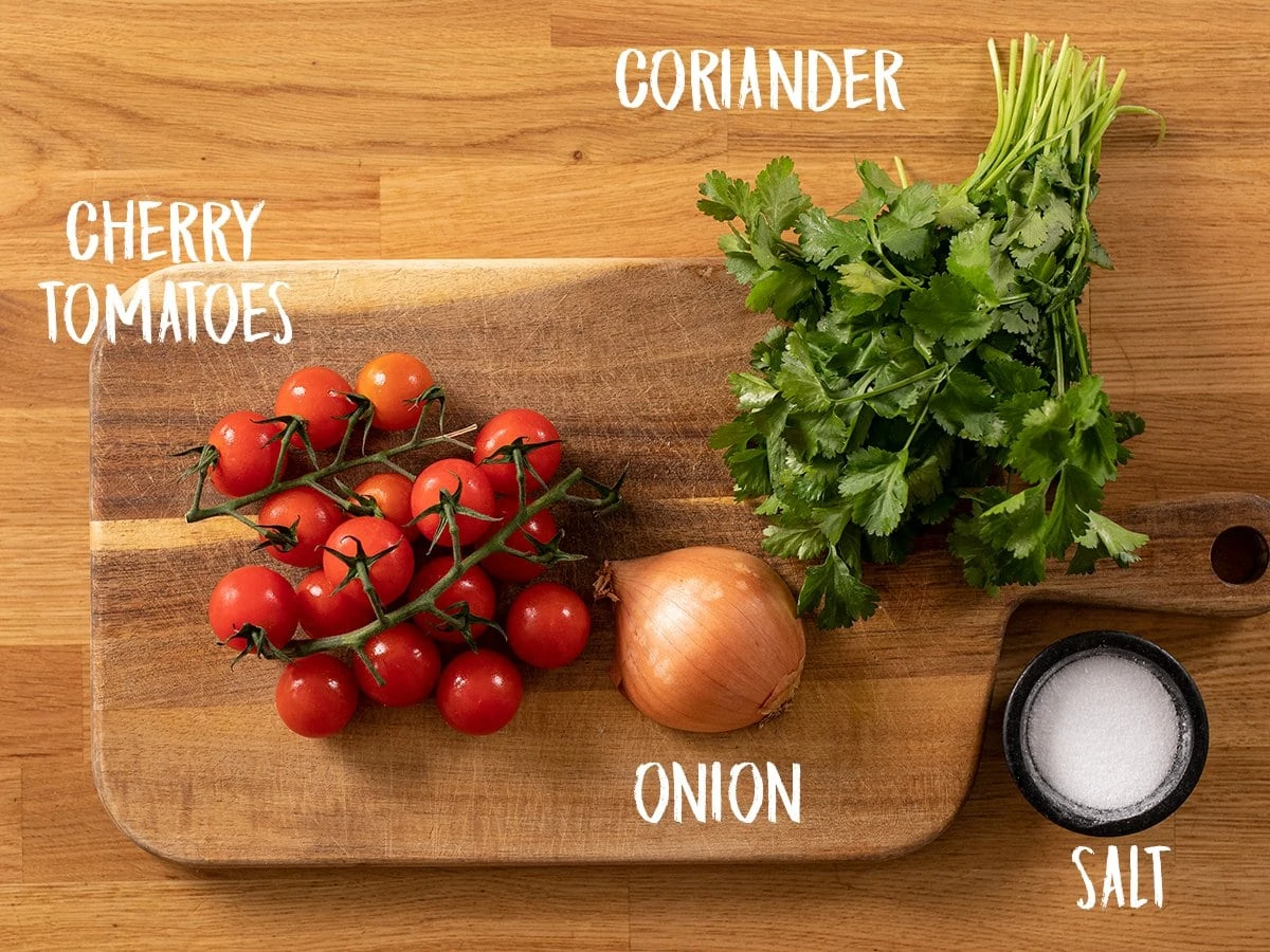 Ingredients for tomato, onion and coriander salad on a wooden table