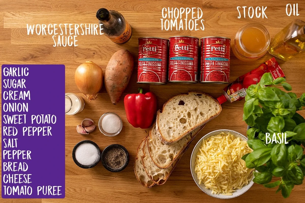 Ingredients for tomato soup with basil-topped cheese on toast on a wooden table