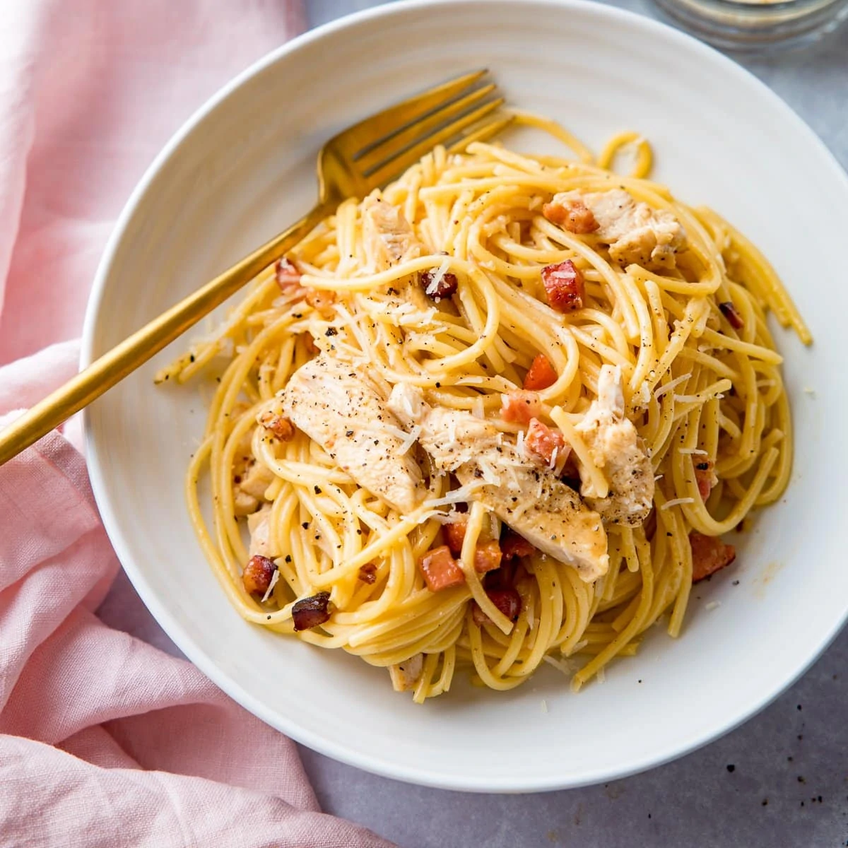 chicken carbonara in a white bowl with a gold fork