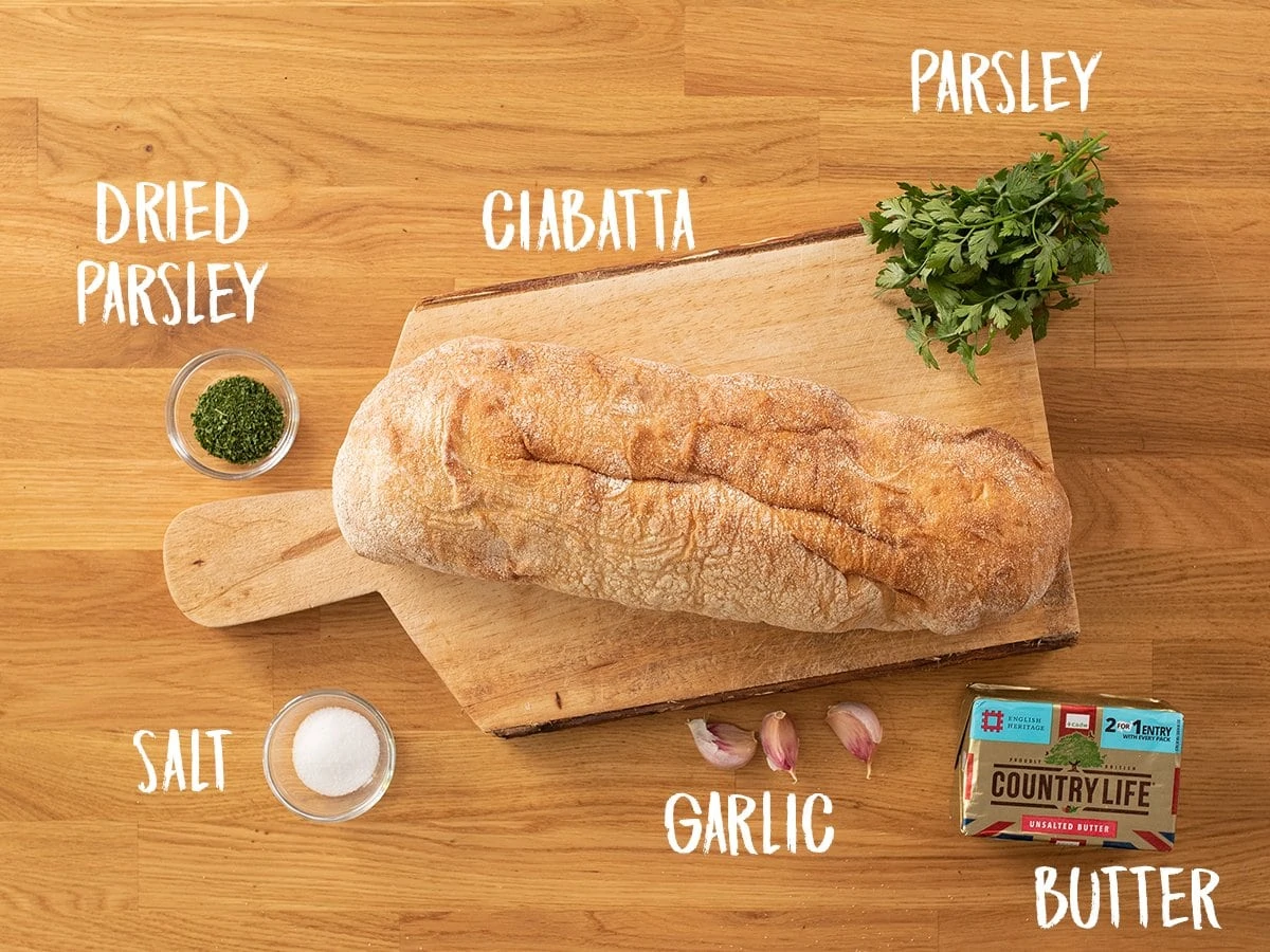 Ingredients for making garlic bread on a wooden table