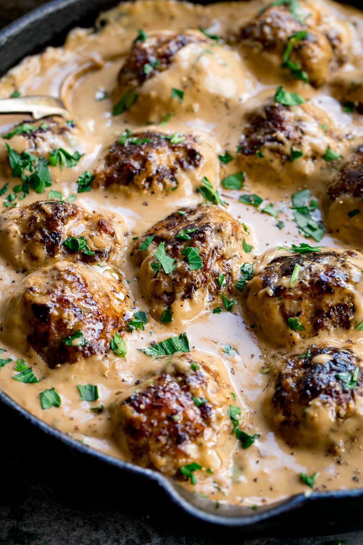 Close up of Swedish meatballs and gravy in a pan topped with parsley