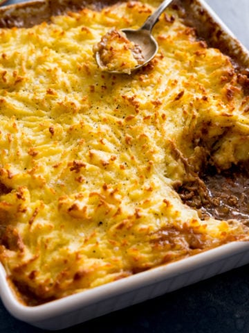 Shepherd's pie in a white dish with a portion taken out.