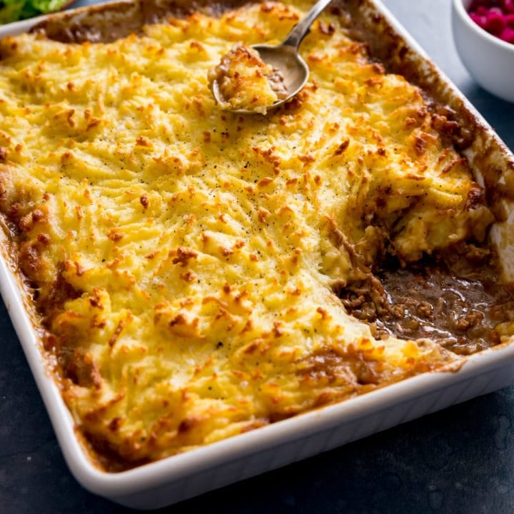 Shepherd's pie in a white dish with a portion taken out.