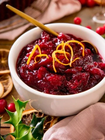 Cranberry sauce in a white bowl with orange zest on top - on a festive christmas table