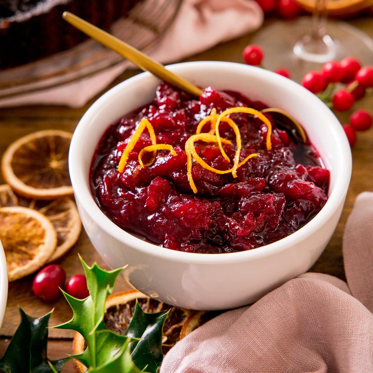 Cranberry sauce in a white bowl with orange zest on top - on a festive christmas table