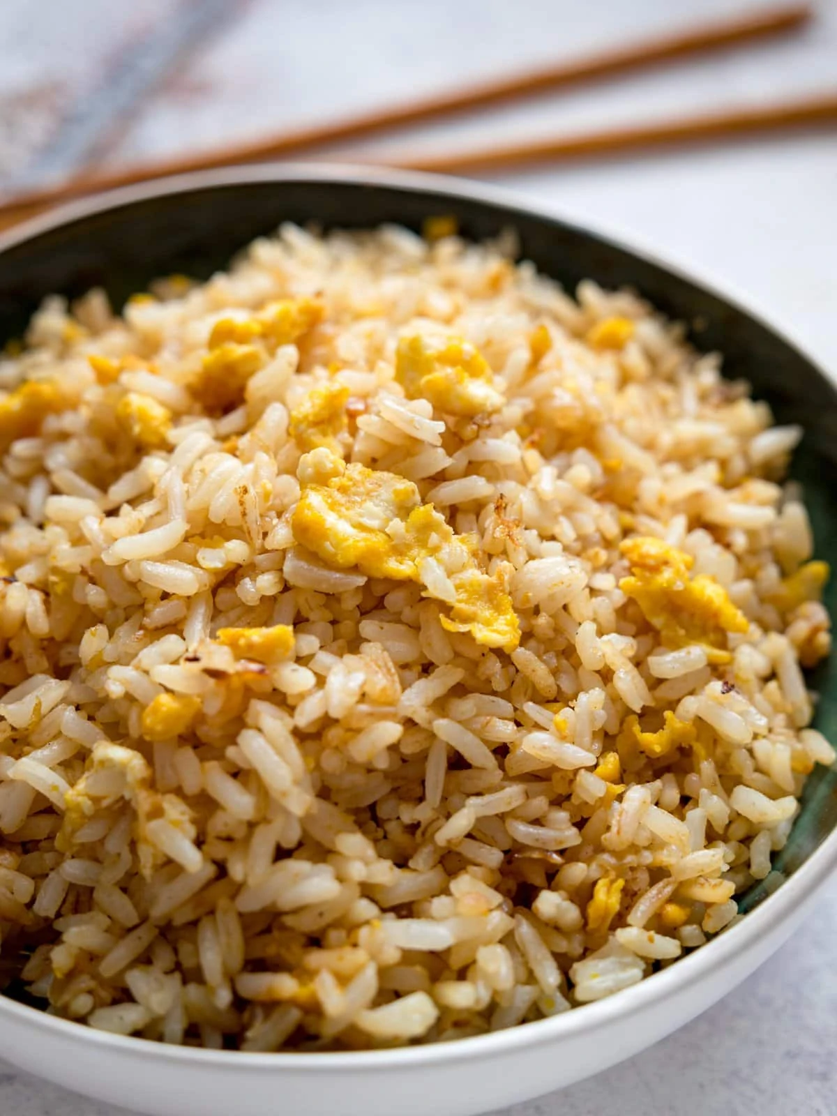 Egg fried rice in a bowl with chopsticks in the background