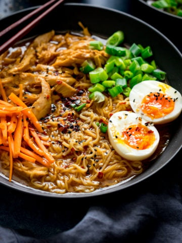 Chicken Ramen in a black bowl topped with egg, carrots and spring onions