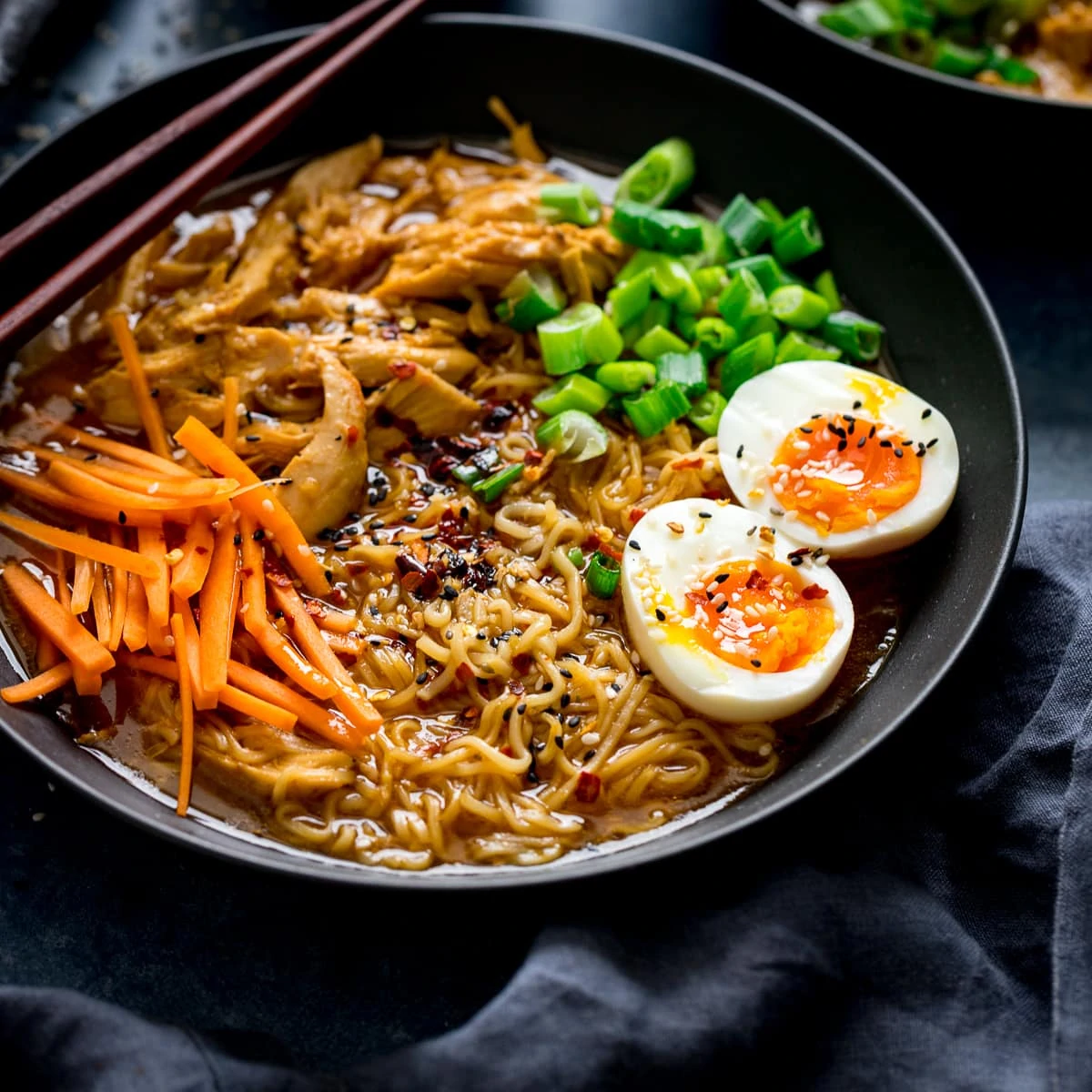 Chicken Ramen in a black bowl topped with egg, carrots and spring onions