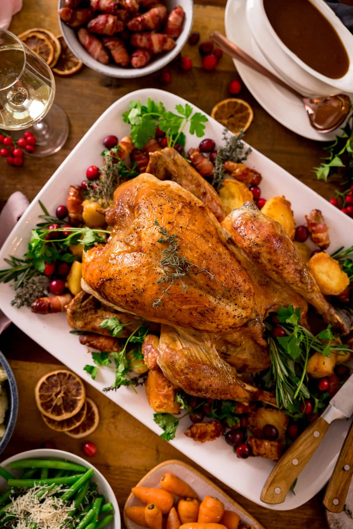 Roast turkey on a white rectangular plate surrounded by side dishes.