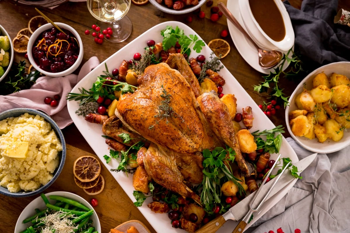 Roast turkey christmas dinner with vegetables and gravy on a wooden table.