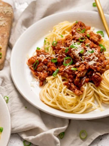 leftover turkey bolognese on a white plate with spaghetti