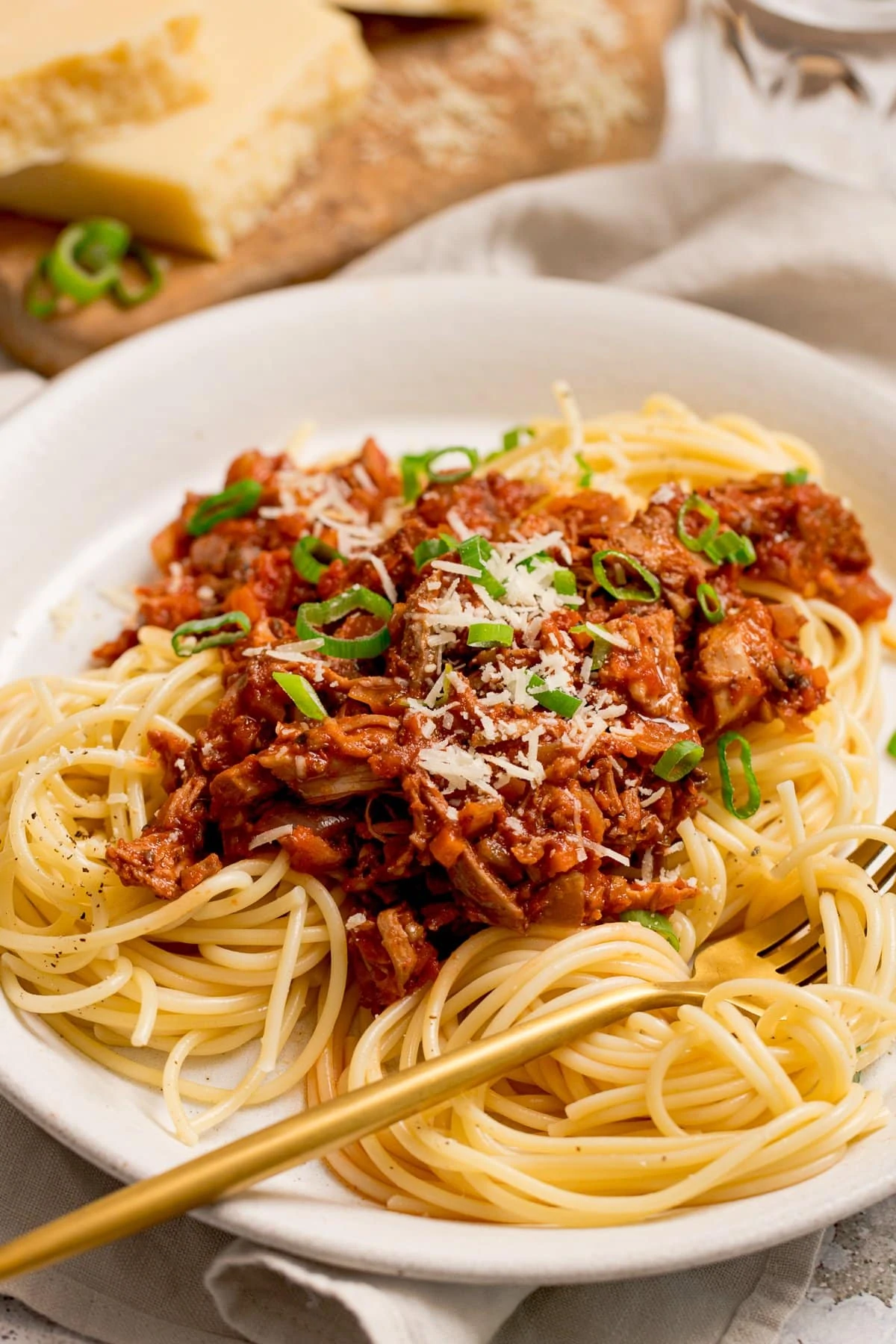 leftover turkey bolognese on a white plate. Gold fork resting on the plate.