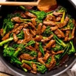 beef and broccoli stir fry in a pan with a wooden spoon