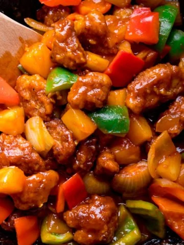sweet and sour pork with peppers in a wok