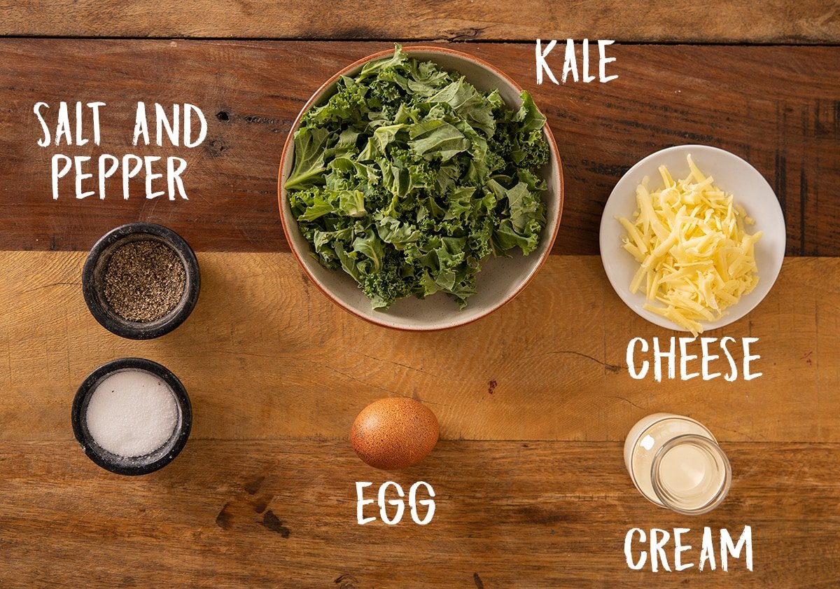 Ingredients to make creamy eggs and kale on a wooden board.