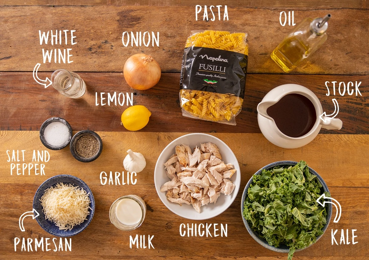 Ingredients for a one pot chicken pasta recipe laid out on a wooden table with titles superimposed on.