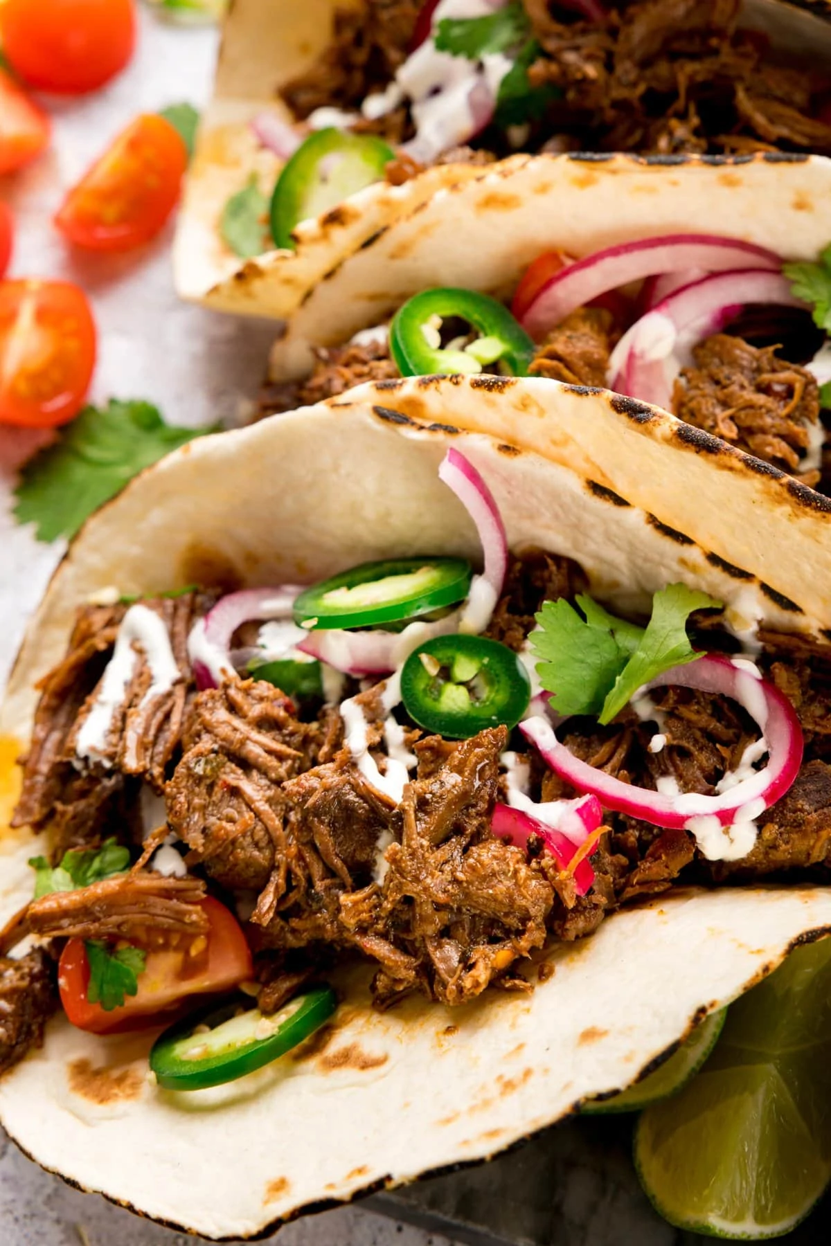 Close up of a beef barbacoa taco with jalapeno and red onion toppings