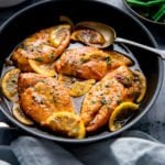 Square image of a dark pan filled with honey lemon chicken.