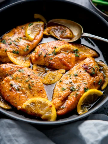 Square image of a dark pan filled with honey lemon chicken.