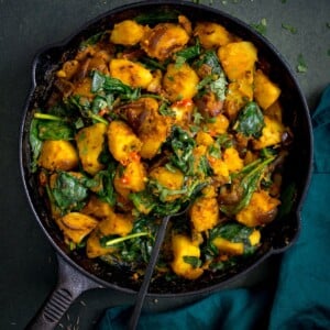saag aloo in a black pan on a dark background