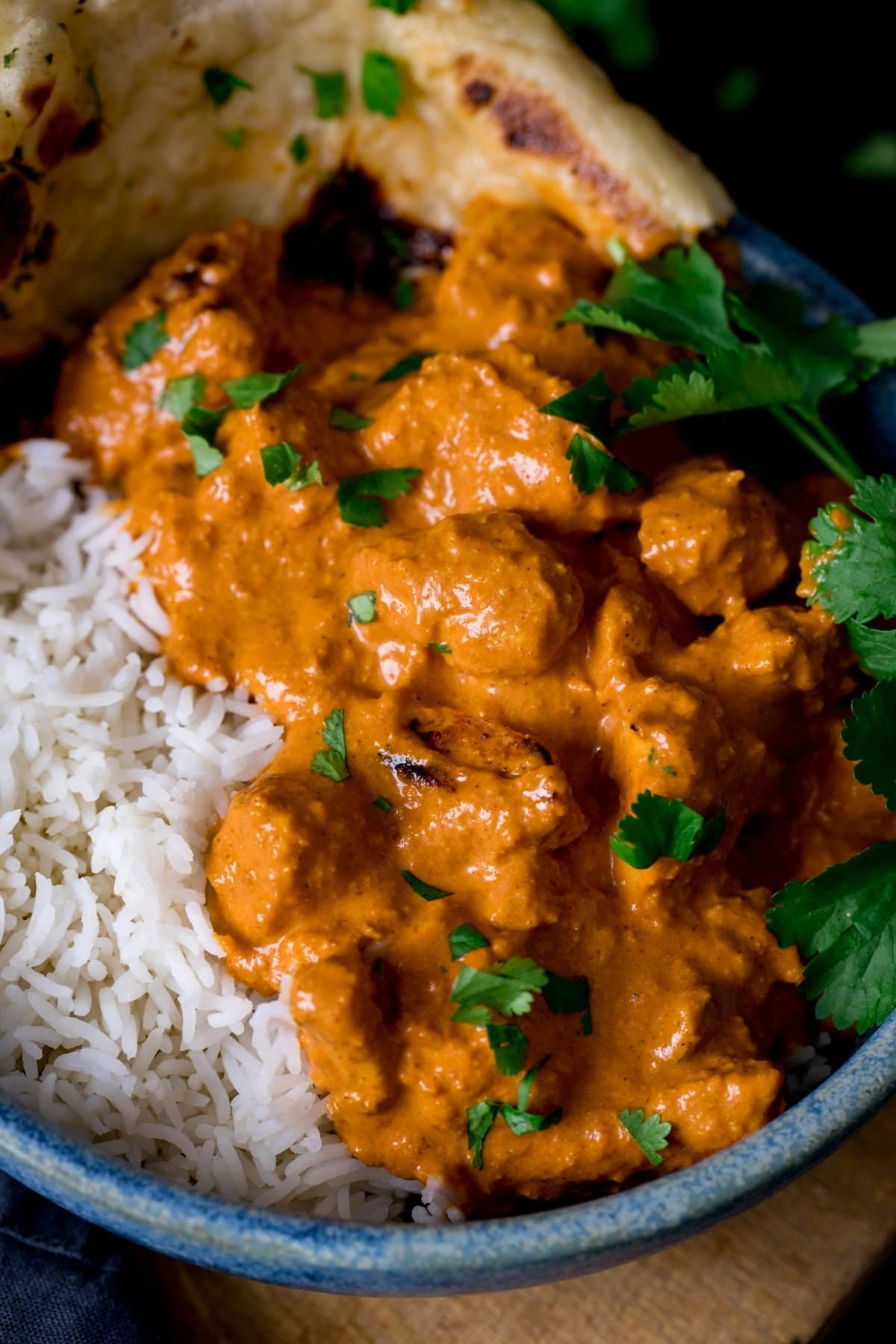 Butter chicken in a bowl with rice and naan bread.