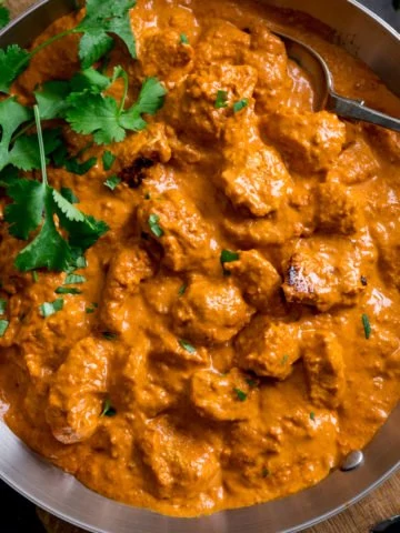Butter Chicken in a pan with fresh coriander.