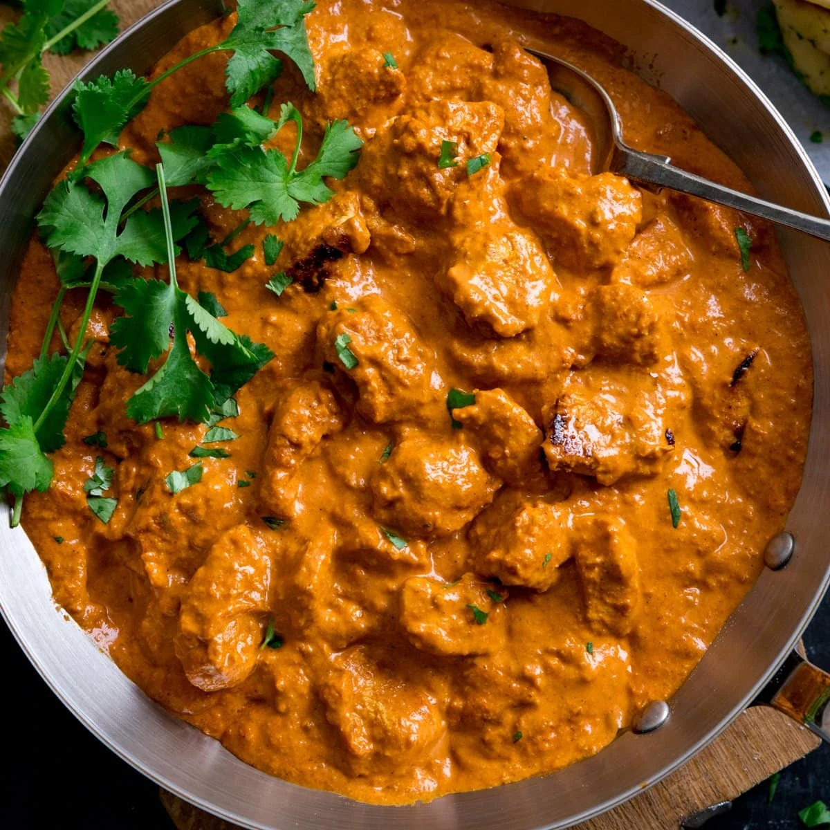 Butter Chicken in a pan with fresh coriander.